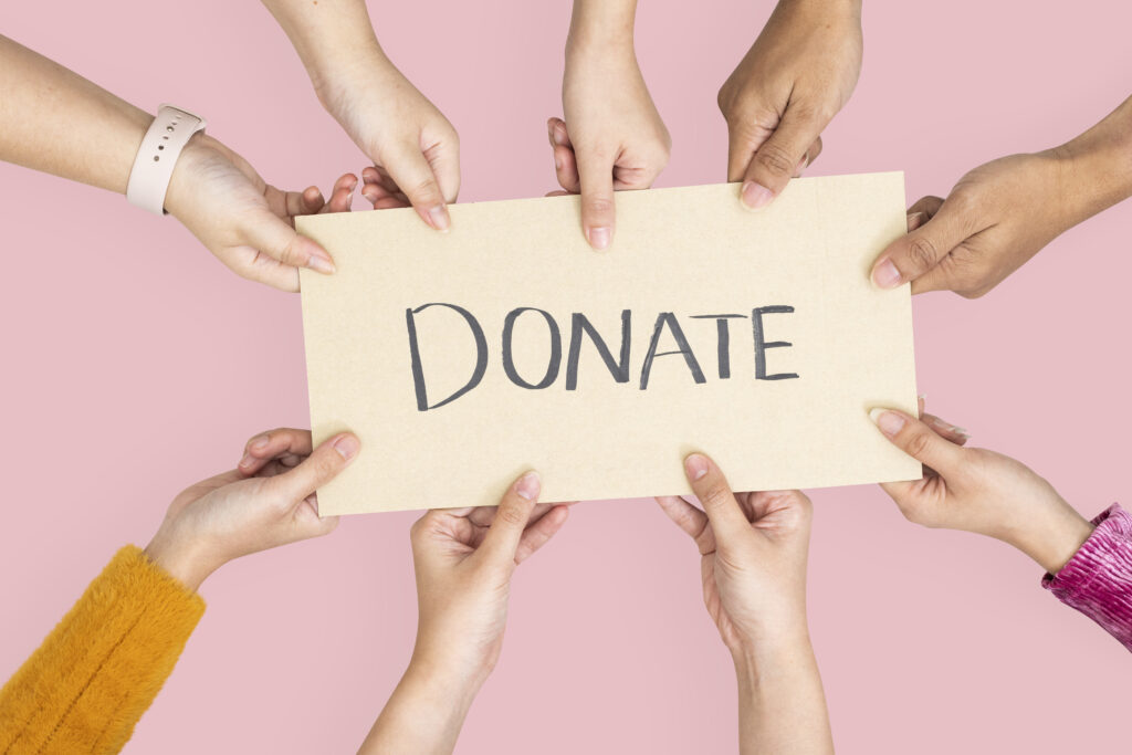 mains tendues portant un papier avec écrite "donate"